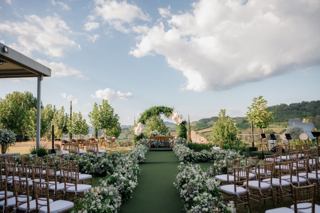 Beautiful outdoor wedding ceremony setup featuring a floral arch, decorated aisle and guest seating.